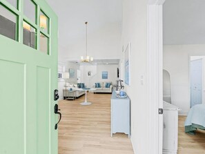 Ein modernes Hotelzimmer mit grüner Tür, einem weißen Bett, einem Schreibtisch und einem Sofa.