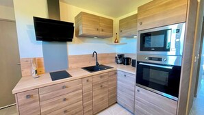 Een moderne keuken met houten kastjes, een ingebouwde magnetron, een koffiezetapparaat en een zwart aanrecht.