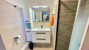 Een badkamer met toilet, wastafel en douche.