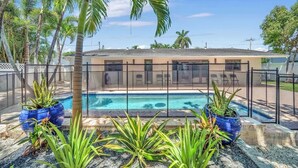 A pool area with a house in the background, surrounded by palm trees and potted plants. - Casa Mimosa Family Tropical Oasis with Pool (Miami)