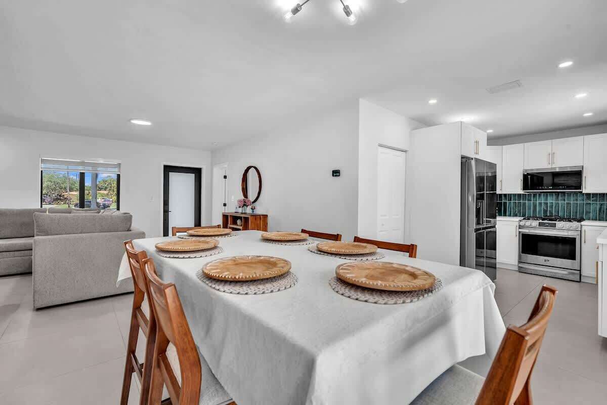 A modern kitchen with white cabinets, stainless steel appliances, and a dining area with a table set for four.
