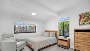 A bedroom with a bed, a chair, a wooden dresser, a nightstand, and a window with a view. - Casa Mimosa Family Tropical Oasis with Pool (Miami)