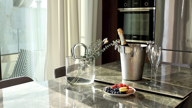 A marble table with a champagne bottle, glasses, and a plate of fruit. - Alimos Escape 3 (Alimos)