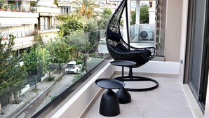 A balcony with a hanging chair, two small tables, and a view of the cityscape. - Alimos Escape 3 (Alimos)