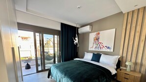 A modern hotel room with a large bed, a view through a sliding door, a ceiling fan, and a wall-mounted air conditioner. - Alimos Escape 3 (Alimos)