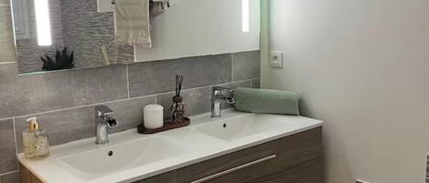 A bathroom with a double vanity, a large mirror, and a modern design.