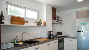 A modern kitchen with a stainless steel refrigerator, a microwave, a coffee maker, and a wooden cutting board on the counter. - Villa Marina Blanca - elegance and tranquillity right on the harbor (Islas Baleares)