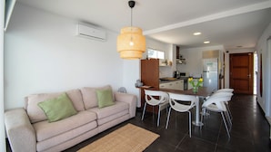 A modern living room with a sofa, dining table, chairs, and a kitchen in the background. - Villa Marina Blanca - elegance and tranquillity right on the harbor (Islas Baleares)
