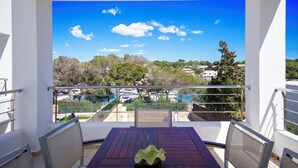 A balcony with a table and chairs, overlooking a scenic view of trees and buildings. - Villa Marina Blanca - elegance and tranquillity right on the harbor (Islas Baleares)