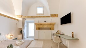 Ein Schlafzimmer mit Bett, Schreibtisch, Sessel, Fernseher und Kamin.