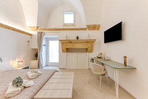 Een slaapkamer met een bed, een bureau, een stoel, een televisie en een open haard.