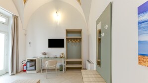 A room with a flat-screen TV, a desk with a chair, a small table, a coat rack, and a large mirror. - Room 'Casa Sant'Anna 2' with Air Conditioning (Presicce)