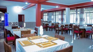 A restaurant with multiple tables and chairs, a tiled wall, and large windows. - Kinindo Light Hotel (Bujumbura)