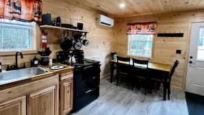 Een houten keukentje met een kookplaat, spoelbak en eethoek.