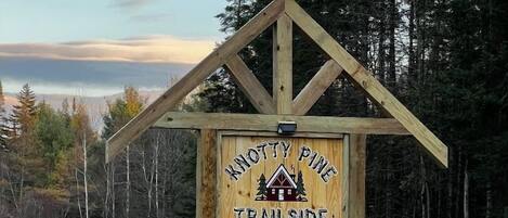 A wooden sign with 'KNOTTY PINE TRAILSIDE CABINS' and a phone number.