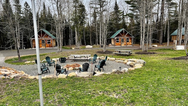 Een lodge met twee huisjes, buitenmeubilair, een vuurplaats en een picknicktafel.