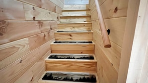 Een houten trap met een leuning, die naar een hoger niveau leidt.