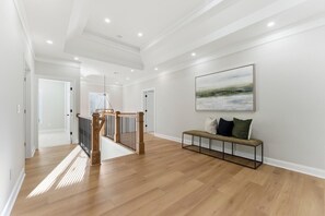 A spacious hallway with wooden flooring, a staircase with wooden railings, and a bench with cushions. - A newly constructed home with four bedrooms and four bathrooms. (Chamblee)