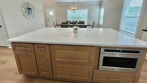 Una cocina con isla central, armarios de madera, horno empotrado e iluminación colgante.