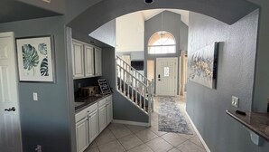 A hallway with a staircase, a kitchen area, and a dining area. - Luxury Lakefront Retreat Fire Pit, Mountain Views & Resort Amenities (Goodyear)
