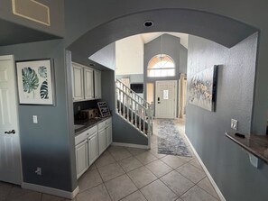 A hallway with a staircase, a kitchen area, and a dining area. - Luxury Lakefront Retreat Fire Pit, Mountain Views & Resort Amenities (Goodyear)