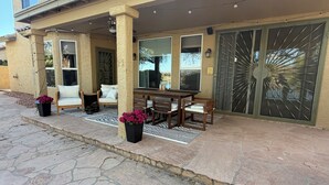 A covered patio with a stone floor, a dining table with chairs, and a large window. - Luxury Lakefront Retreat Fire Pit, Mountain Views & Resort Amenities (Goodyear)