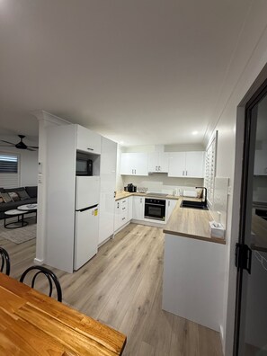 Une cuisine moderne avec des armoires blanches, un plan de travail en bois et un four encastré.