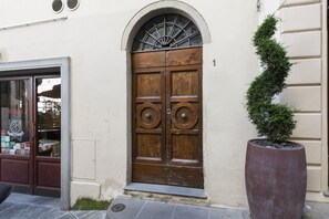 A wooden double door with a decorative arch above it, a potted plant beside the door, and a building number '1' on the wall. - Lovely Nest by MMega Homes and Villas (Florence)