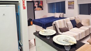 A compact living space with a kitchenette, a dining area, and a bed. - Studio Pé na Areia - Channel 4 (Santos)