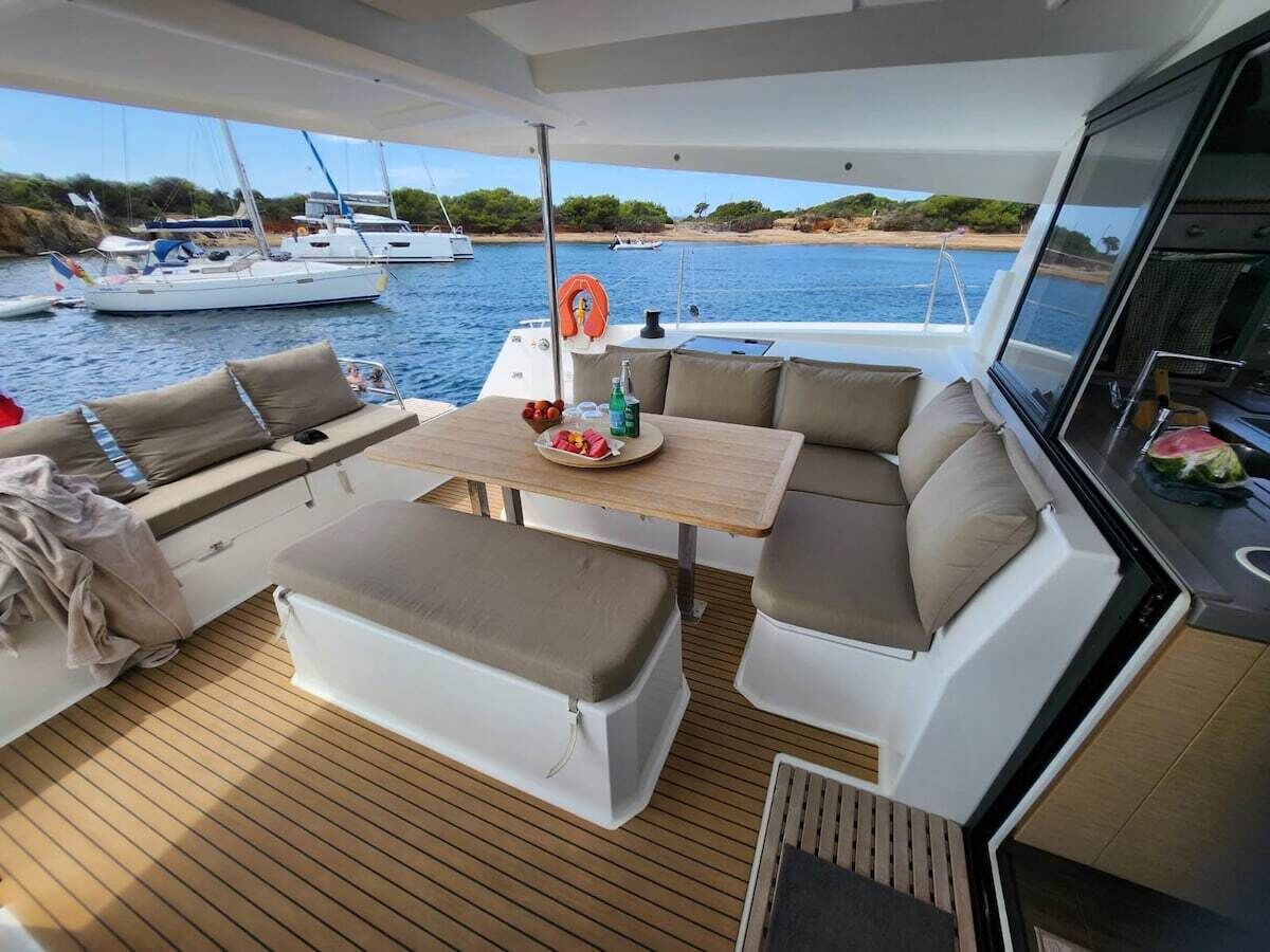 Das Deck einer Yacht mit Essbereich, Sitzgelegenheiten und Blick auf das Wasser.