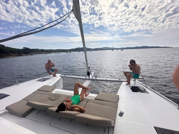 A boat with a sun deck, lounge chairs, and people relaxing.