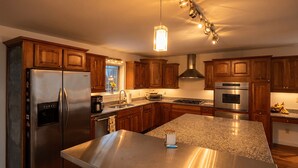 Una cocina moderna con electrodomésticos de acero inoxidable, gabinetes de madera y una encimera de granito.
