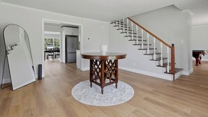 A spacious living area with a wooden staircase, a round wooden table, and a white rug. - Wildmeade Ranch A Luxury Farmhouse on 18 Acres (Leary)