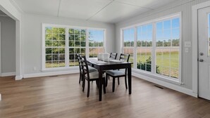 A dining area with a table and chairs, large windows, and a view of the outdoors. - Wildmeade Ranch A Luxury Farmhouse on 18 Acres (Leary)