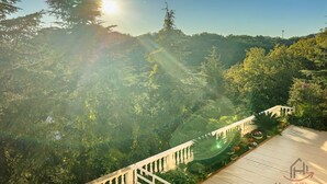 A view of a forested hillside with a wooden deck and railing.