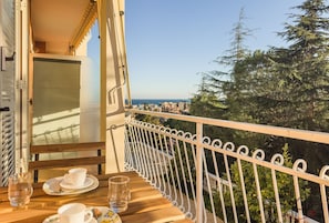 A balcony with a table set for two, overlooking a coastal cityscape and dense greenery. - [Ceriale for Fun] AquaPark & Beaches 5min • A/C (Ceriale)