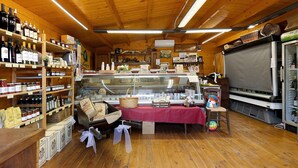 A wooden interior with shelves of bottles, a table with a red cloth, and a refrigerator.
