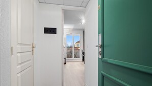 A hallway with a white door, a green door, and a view into a balcony area. - Apartment Near the Center of Grasse (Grasse)