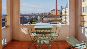 A balcony with a table and chairs, a view of buildings, and a chimney. - Apartment Near the Center of Grasse (Grasse)