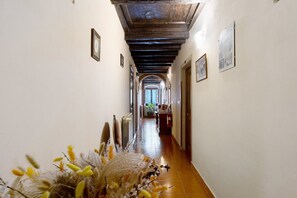 Un corridoio con soffitto in legno, quadri appesi alle pareti e un termosifone a pavimento.