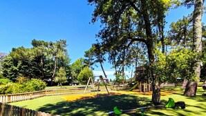 Une aire de jeux avec des balançoires, un toboggan et une balançoire à bascule.