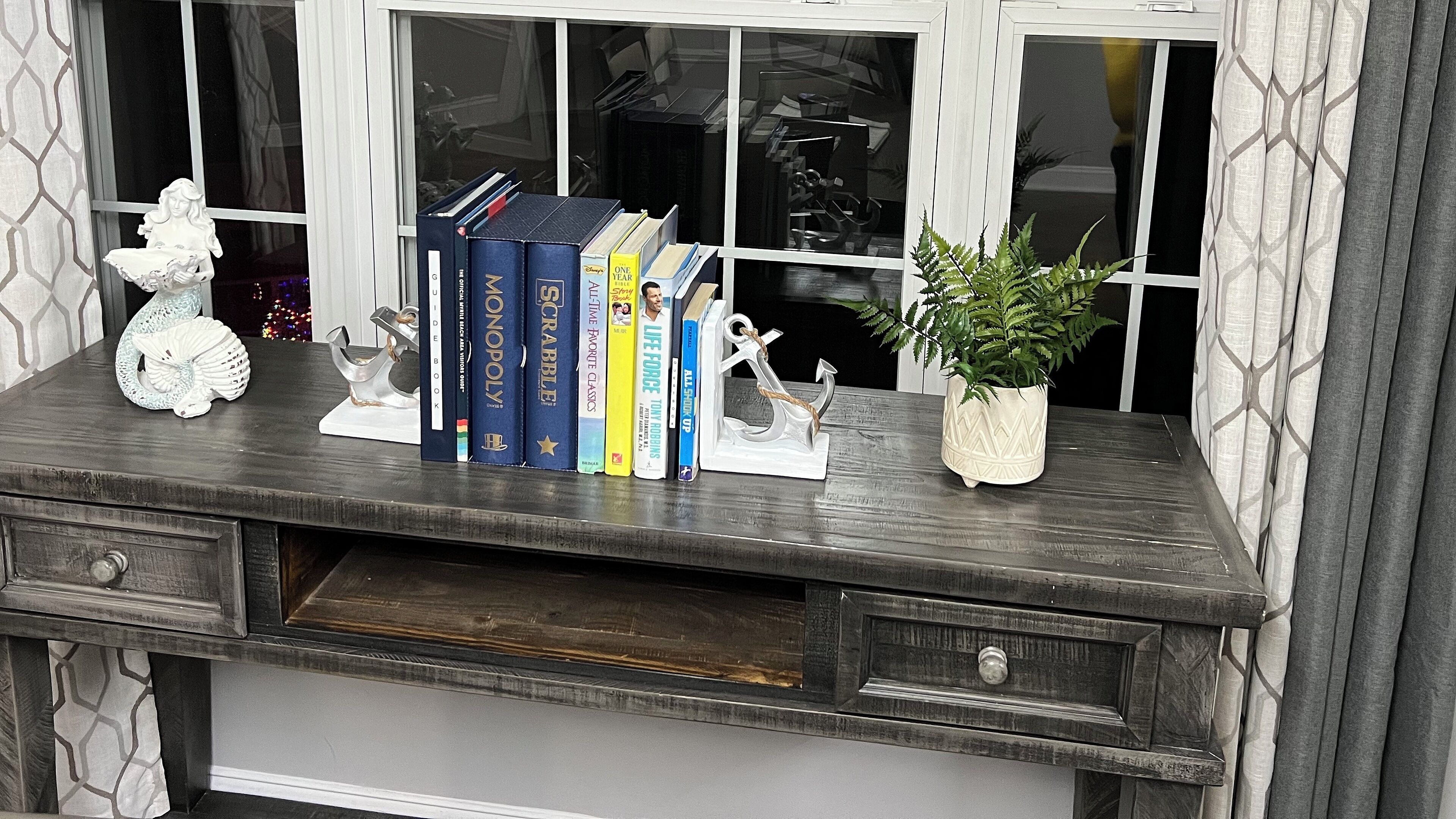 Escritorio de madera con una planta, libros y objetos decorativos.