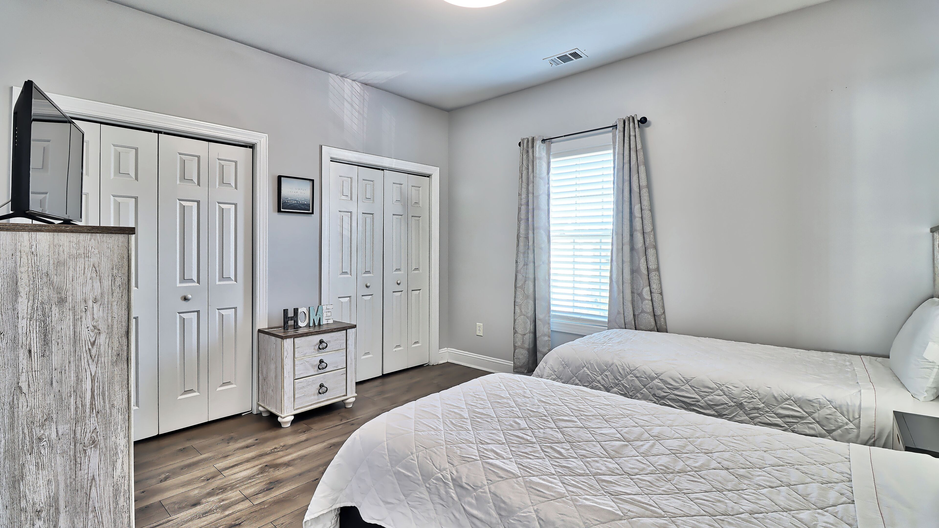 A bedroom with two beds, a dresser, and a wardrobe.