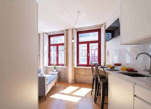 A compact kitchen with a dining area, a sofa, and a small table with a potted plant. - Modern Studio with Terrace & Jacuzzi by HostWise (Porto)