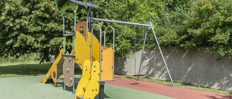 A playground with a yellow climbing structure and a red pathway.
