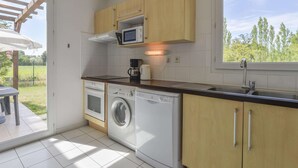 A compact kitchen with a microwave, coffee maker, washing machine, and a window with a view of greenery. - Provence Villa for 8 With Private Pool (Saint-Saturnin-les-Avignon)