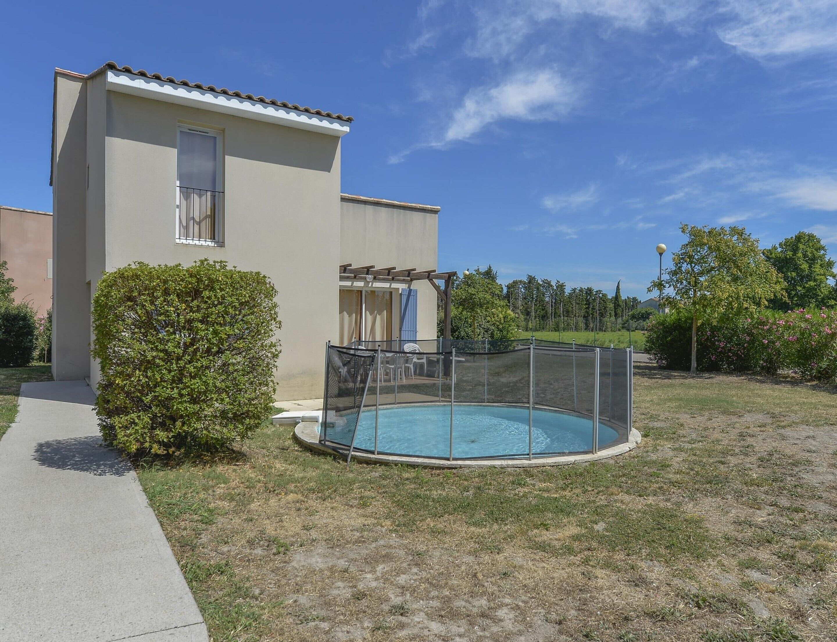 A building with a swimming pool, a covered patio, and a fenced area.