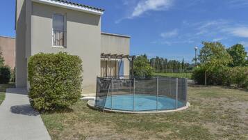 A building with a swimming pool, a covered patio, and a fenced area.