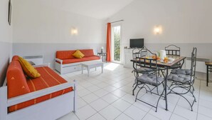 A room with a sofa, dining table, chairs, a TV, and a window with curtains. - Provence Villa for 8 With Private Pool (Saint-Saturnin-les-Avignon)