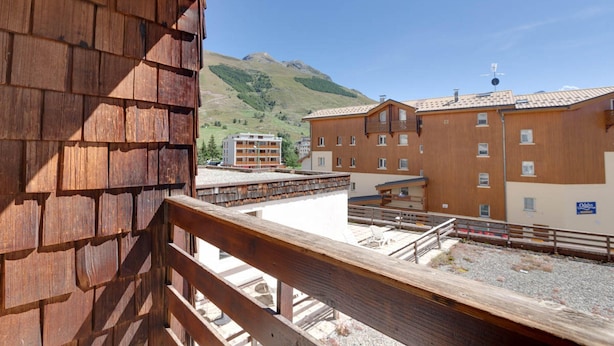 A wooden balcony overlooking a mountainous area with buildings in the background. - Cosy Apartment 150 m From ski Slopes (Les Deux Alpes)